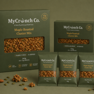 A product lineup of MyCrunch Co. Maple Roasted Cluster Mix featuring a Family Box, a Standard Pack box, and three single-serve snack pouches displayed together on a green background with scattered nut-free granola clusters.