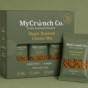 A forest green MyCrunch Co. Maple Roasted Cluster Mix 6-pack box standing next to an individual single-serve snack pouch, showing a window cutout filled with nut-free granola clusters.
